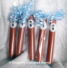 three chocolate sticks wrapped in cellophane and tied with blue ribbon are sitting on a white blanket