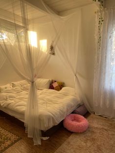 a white bed sitting in a bedroom next to a pink bean bag pillow on top of a wooden floor