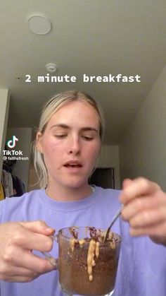 a woman is holding a spoon in her hand and looking at the chocolate dessert she has made