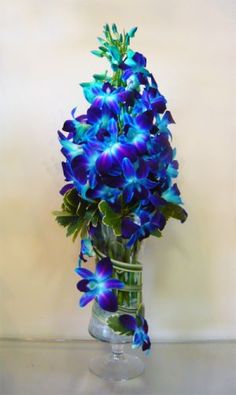 blue flowers are in a clear vase on a table