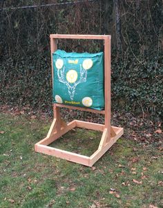 a wooden stand with a green bag on it in the grass next to some bushes