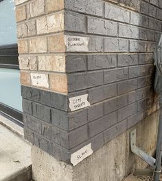 a parking meter on the side of a building next to a brick wall with names written on it