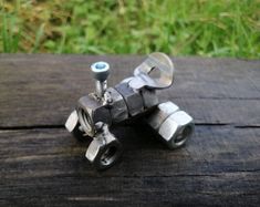 two pieces of metal sitting on top of a wooden table next to grass and bushes