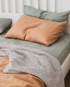 a bed with two pillows on top of it next to a blanket and pillow case