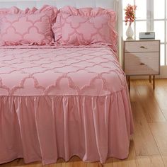 a pink bed with ruffled sheets and pillows