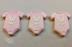 three decorated cookies in the shape of baby onesuits with bunny ears on them