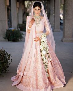 a woman in a pink lehenga and veil