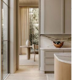 an open door leading to a kitchen with marble counter tops and white cabinets, along with a bowl on the counter