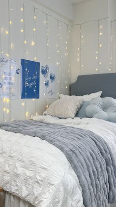 a bed with white sheets and lights on the wall behind it, in a bedroom