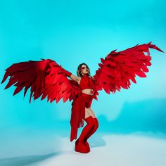 a woman in red is posing with large wings