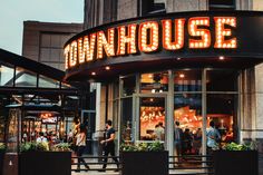 people are walking in front of the entrance to a restaurant with neon lights on it