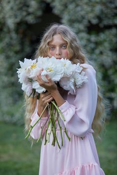 a girl in a pink dress holding white flowers