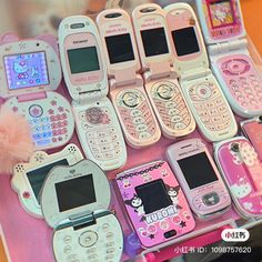 many different types of cell phones are displayed on a pink tablecloth with pom poms