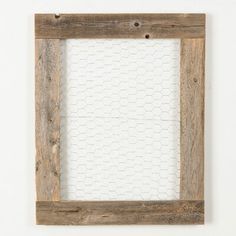 an old wooden frame hanging on the wall with a chicken wire pattern in front of it