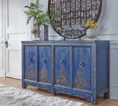 an old blue cabinet with plants on top in front of a mirror and white rug