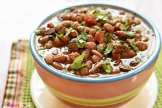 a bowl filled with beans and greens on top of a plate next to a napkin