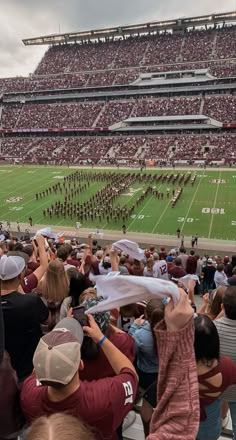 a football stadium filled with lots of people watching a band perform on the sidelines