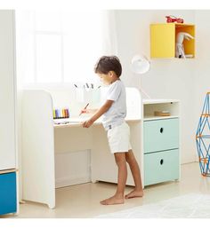 a little boy that is standing in front of a desk