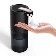 a hand is holding a soap dispenser in front of a black container