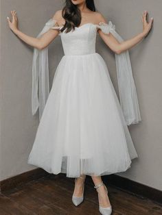 a woman in a white dress is posing with her arms outstretched and hands out to the side