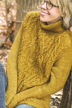 a woman sitting on a tree wearing a yellow sweater