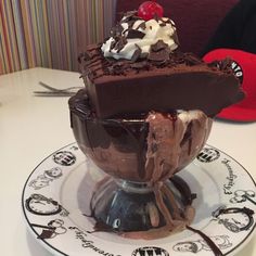 an ice cream sundae on a plate with chocolate sauce and whipped cream in it