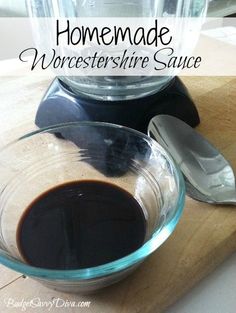 a glass bowl filled with liquid sitting on top of a wooden cutting board next to a blender