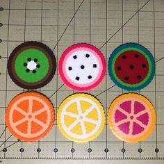 four different colored buttons sitting on top of a piece of paper next to a ruler