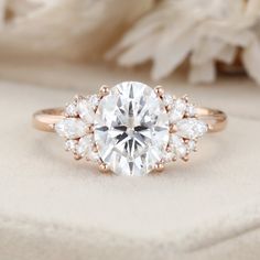 a rose gold ring with an oval cut diamond surrounded by pear shaped diamonds on top