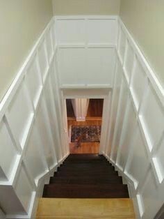 an overhead view of a staircase with white paneling and wood steps leading up to the second floor