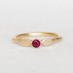 Lovely red ruby and gold petal ring. Two handmade petals frame the 3mm ruby. I gave the 1.6mm yellow gold band a hammered texture and a brushed satin finish. Sweet and elegant. Ruby - 3mm's, heat-treated Band - 1.6mm, hammered Gold - Recycled, eco-friendly - choose between 14k and 18k Finish - Comes with a brushed satin finish (pictured), unless you specify that you want a high polished finish . **Choose between 14k gold and 18k gold when you check out. Thanks for looking! Lilian Yellow Gold Ruby Ring With Lab-created Birthstone, Ruby Birthstone Ring For Promise Occasion, Gold Ruby Birthstone Ring With Rose Cut Diamonds, Red Ruby Ring In 14k Gold With Bezel Setting, Ruby Ring With Bezel Setting And Round Band, Red Ruby Ring With Bezel Setting, Ruby Bezel Setting Ring For Anniversary, Ruby Birthstone Ring With Bezel Setting, Hand Forged Ruby Ring In Red