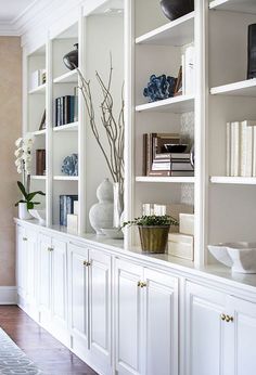 a living room filled with white bookshelves and vases on top of them