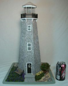 there is a small model of a light house with a soda can next to it