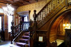 an ornate staircase with chandelier and wood paneling in a home's entryway