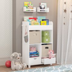 a white book shelf filled with books next to a teddy bear and other toys in a room