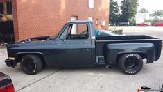 an old pickup truck parked in front of a brick building