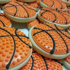 basketball cookies with orange icing and black sprinkles are on a table