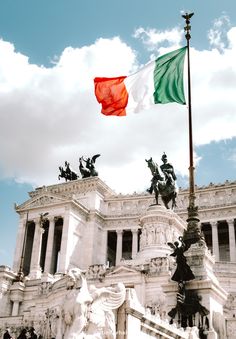 an italian flag flying in front of a building with statues on the sides and columns