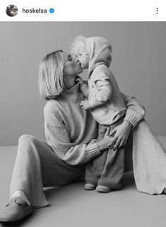 a woman sitting on the ground kissing a baby