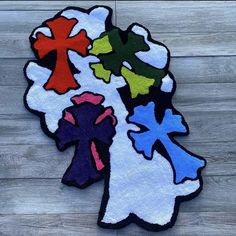 an area rug with different colored crosses on the top and bottom, in front of a wood background