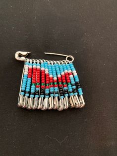 the beaded bracelet is hanging from a hook on a black surface with a red, white and blue design