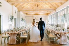 the bride and groom are walking towards each other in front of tables set with white linens