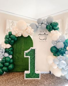 a green and white balloon arch with the number one on it