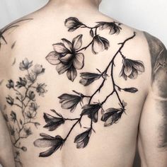 the back of a man's shoulder with flowers and leaves tattooed on his chest