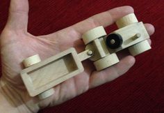 a hand holding a wooden toy with wheels