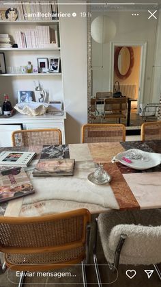 a dining room table and chairs with magazines on it