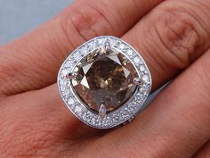 a woman's engagement ring with a brown diamond surrounded by white and clear diamonds