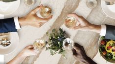 four people holding wine glasses at a dinner table