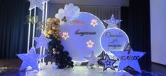 balloons and stars are on display in front of a stage set up for an event