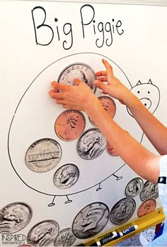 a young boy is drawing on a big piggie coin chart with crayons